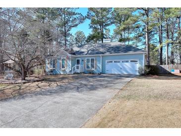 Charming light blue home featuring a manicured lawn and a two-car garage, creating a welcoming curb appeal at 4020 Winchester Way, Loganville, GA 30052