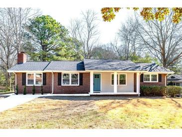 Charming brick home with a well-manicured lawn, front porch, and blue front door at 1523 Vancouver Dr, Tucker, GA 30084