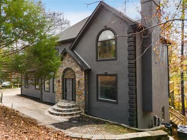 Stunning home exterior featuring stone accents, arched windows, and mature trees at 270 Boulder Dr, Roswell, GA 30075