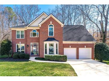 Charming two-story brick home with manicured lawn, two-car garage, and mature landscaping at 565 Ashvale Overlook, Alpharetta, GA 30005