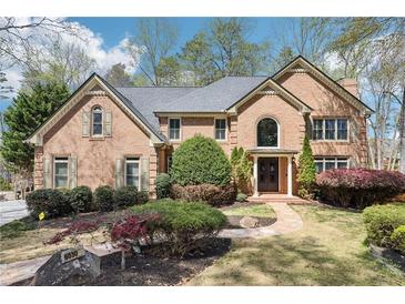 Charming brick home with manicured landscaping and a beautiful stone walkway leading to the entrance at 6030 Chimney Springs Rd, Buford, GA 30518