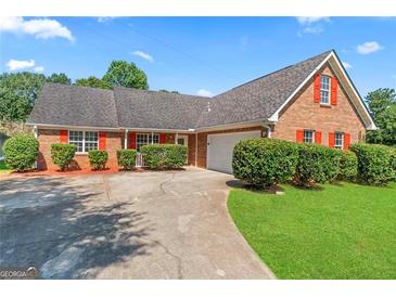 Charming brick home featuring manicured landscaping, a spacious driveway, and a two-car garage at 217 Crystal Ct, Hampton, GA 30228