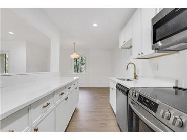 Bright kitchen features white cabinetry, stainless steel appliances, stone countertops, and gold hardware at 2396 Lawrenceville Hwy # V, Decatur, GA 30033