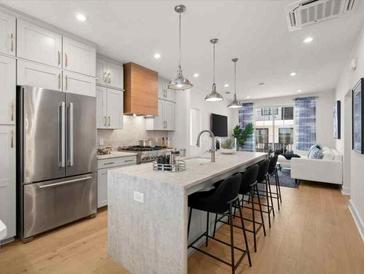 Open concept kitchen with stainless steel appliances, a center island with seating, and a view of the living area at 201 New St # 2207-1, Decatur, GA 30030