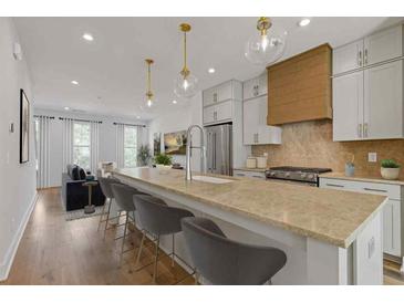 Bright, open kitchen boasts a large island, stainless steel appliances, and modern pendant lighting at 201 New St # 2305-1, Decatur, GA 30030
