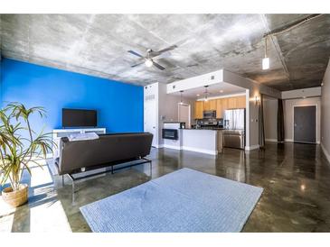 Open-concept living space with polished concrete floors, a modern sofa, and a bright blue accent wall at 845 Spring Nw St # 322, Atlanta, GA 30308