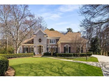 Imposing two-story brick home with manicured lawn and mature trees exuding curb appeal and classic charm at 715 Newport Holw, Alpharetta, GA 30005