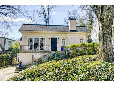 Charming brick home featuring an arched front door, landscaped yard, and classic architectural details at 231 Peachtree Ne Way, Atlanta, GA 30305