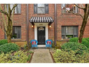 Charming brick condo with a striped awning, front door and blue chairs with red pillows at 694 Argonne Ne Ave # 4, Atlanta, GA 30308
