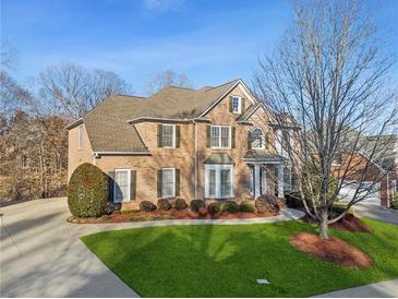 Beautiful two-story brick home with a well-manicured lawn and a large driveway on a sunny day at 3690 Millwater Xing, Dacula, GA 30019