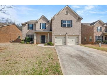 Charming two-story brick home featuring a two-car garage, front porch, and well-manicured lawn at 3257 Alhambra Cir, Hampton, GA 30228