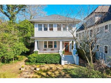 Charming two-story home with inviting front porch and landscaped yard surrounded by mature trees at 565 Candler St, Atlanta, GA 30307