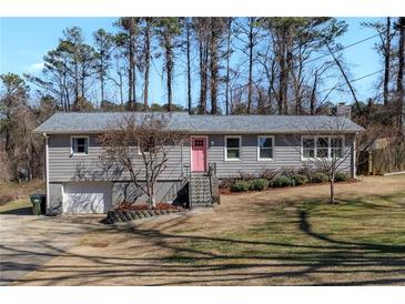 Charming single-story home with a pink front door, landscaped yard, and inviting curb appeal at 2007 Manassas Dr, Woodstock, GA 30189