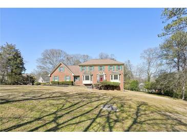 Charming two-story brick home featuring green shutters, a manicured lawn, and a welcoming red front door at 4805 Mystere Sw Ln, Lilburn, GA 30047