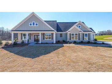 Charming single-story home featuring a covered front porch, stone accents, and manicured lawn at 5410 Crow Dr, Cumming, GA 30041