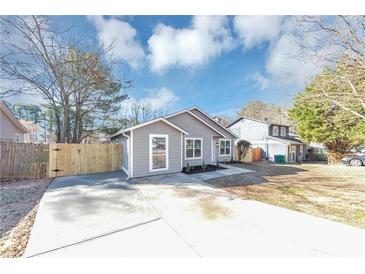 Charming one-story home featuring gray siding, a well-manicured yard, and a concrete driveway at 6042 Creekford Dr, Lithonia, GA 30058