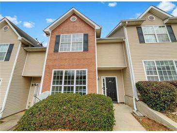 Inviting townhouse with a mix of brick and vinyl siding, featuring large windows and well-maintained landscaping at 1485 Riverrock Trl, Riverdale, GA 30296