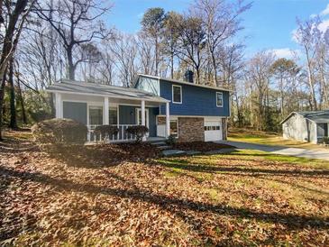 Inviting two-story home featuring a cozy front porch and attached garage, nestled amongst mature trees at 5407 Effingham Ct, Lithonia, GA 30038