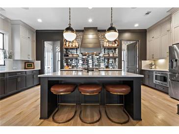 Modern kitchen features pendant lights, a large island with seating, and mirrored backsplash detail at 3475 Landen Pine Ne Ct, Atlanta, GA 30305