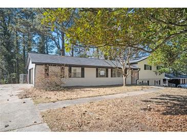 Ranch-style home featuring brick exterior, black shutters, and mature trees in a tranquil setting at 1887 King Charles Sw Rd, Atlanta, GA 30331