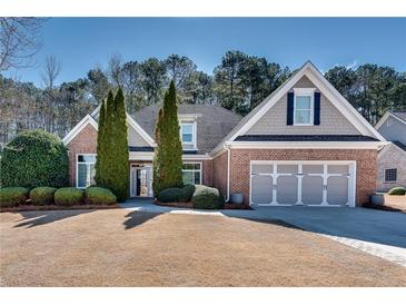 Charming brick home with a manicured front yard, three-car garage, and mature landscaping at 2477 Misty Rose Ln, Loganville, GA 30052