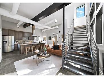 Open-concept living space with modern kitchen, stainless steel appliances, metal stairs, and industrial-chic design at 307 Cherokee Se Ave # 9, Atlanta, GA 30312