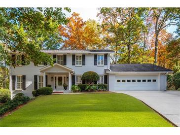 Charming white brick home featuring manicured lawn and mature trees in a desirable neighborhood at 870 Richmond Hill Dr, Marietta, GA 30068