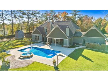 A backyard view of a beautiful home with a pool and hot tub surrounded by a lush green lawn at 650 New Morn Dr, Hampton, GA 30228