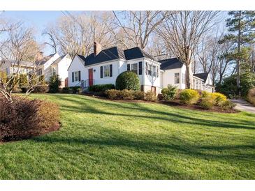 Charming one-story home features a lush front yard with a vibrant red door and mature landscaping at 255 Maple Nw Ave, Marietta, GA 30064