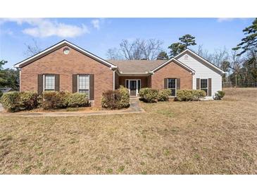 Charming brick home with a well-maintained lawn and mature landscaping in a suburban neighborhood at 1295 Brady Ct, Hampton, GA 30228