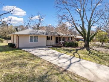 Charming single-story home featuring a brick and vinyl exterior, lush lawn, and extended driveway at 3606 Trickum Ne Rd, Marietta, GA 30066