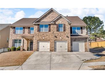 Inviting two-story brick home featuring a three-car garage, lush lawn, and a classic design at 4869 Locherby Dr, Fairburn, GA 30213