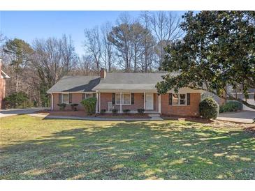Charming brick ranch home with a well-manicured front yard, mature trees, and a cozy front porch at 3540 Honeycomb Se Dr, Conyers, GA 30094