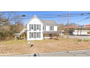 Two-story home featuring black shutters and a quaint porch with a nearby gas station at 700 W College St, Bowdon, GA 30108