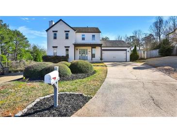 Beautiful two-story home with a well-maintained lawn, an attached garage, and a charming front porch entry at 5065 Timberbridge Ln, Johns Creek, GA 30022