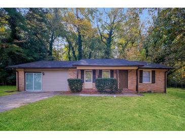 Charming single-story brick home featuring a well-maintained lawn, and attached garage at 5411 Louis Xiv Ln, Atlanta, GA 30349