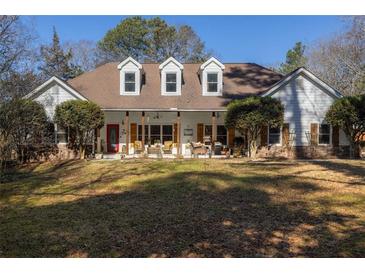 Charming ranch-style home with a covered porch and inviting red door, surrounded by mature trees and a spacious lawn at 3890 Irwin Bridge Nw Rd, Conyers, GA 30012