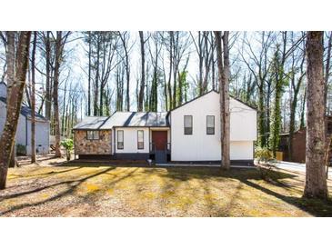 Charming home featuring stone accents, white siding, and a well-maintained front yard surrounded by mature trees at 5199 Mainstreet Park Dr, Stone Mountain, GA 30088