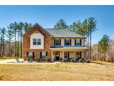 Charming two-story home with brick accents, a covered porch and a well-maintained landscaped front yard at 60 Bridgemill Dr, Covington, GA 30014