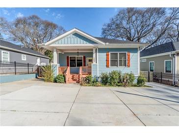 Charming blue home featuring red shutters, a spacious driveway and welcoming porch at 1057 Regent Sw St, Atlanta, GA 30310