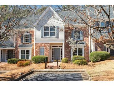 Charming townhome featuring a brick facade, complemented by stylish gray accents, lush landscaping, and inviting entrance at 312 River Glen Dr, Roswell, GA 30075
