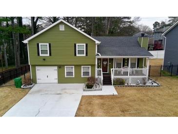Charming two-story home with a well-manicured lawn, inviting front porch, and a convenient one car garage at 2102 Bedford Ct, Lithonia, GA 30058