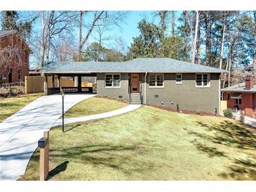 Charming home featuring a well-maintained lawn, gray brick, long driveway, and a convenient carport at 2569 Woodhill Ln, Atlanta, GA 30344