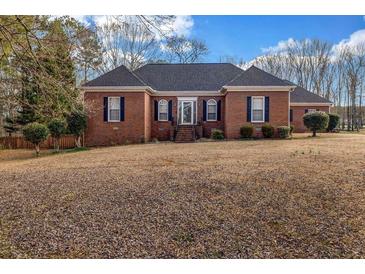 Charming red brick home with a dark roof, set on a spacious lawn with mature trees and manicured bushes at 1450 Brandy Shoals Se Dr, Conyers, GA 30013