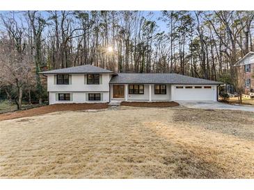 Charming home boasts a freshly painted white exterior, complemented by black trim and a lush, green backdrop at 2490 Brookcliff Ne Way, Atlanta, GA 30345