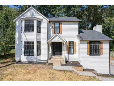 Charming two-story home featuring black windows, shutters, and a well-maintained, landscaped yard at 557 Old Friar Tuck Ln, Stone Mountain, GA 30087