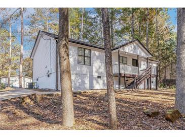 Charming home featuring a quaint front porch and stairs nestled within a wooded landscape at 7155 Pineneedle Drive Sw, Covington, GA 30016