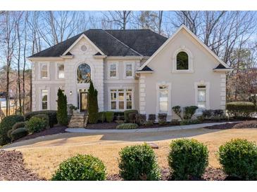 Elegant two-story home with a stone and stucco facade, manicured landscaping and arched windows at 825 Autry Landing Cir, Alpharetta, GA 30022