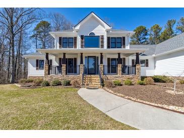 Charming two-story home featuring a welcoming front porch, stone accents, and manicured landscaping at 684 Old Cumming Rd, Sugar Hill, GA 30518