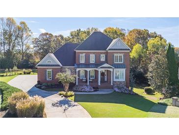 Stately brick home with lush landscaping, circular driveway, and welcoming covered front porch at 3955 Graystone Preserve Pl, Cumming, GA 30040